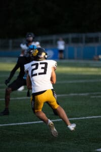 American football player in yellow shorts and helmet running on field during a game.