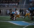 Football players in action during a game, with one player tackling another on the field.