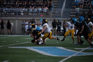 Football players in action during a game, with one player tackling another on the field.