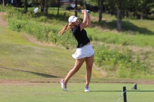 Golfer swings club on a sunny day, showcasing perfect form on green course.