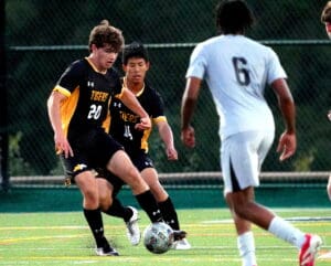 Soccer players in action on the field, team Tigers in black jerseys competing for the ball against opponents in white.