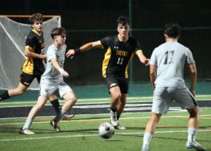 Soccer players in action during a night match, focused on ball control and teamwork on the field.