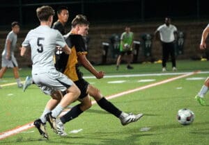 Soccer players in action on the field under lights, engaging in an intense match for the ball.