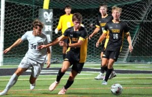 Soccer players in action on the field, competing for the ball under stadium lights.