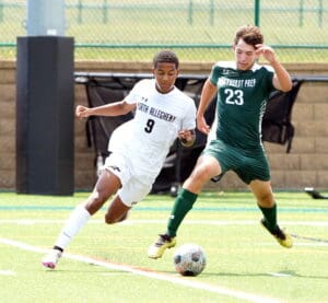 Two soccer players from opposing teams competing for the ball on a sunny sports field.