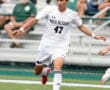Soccer player in white uniform with North Allegheny dribbles ball on field during a game, fans in background.