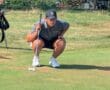 Golfer lining up a putt on a sunny day at the golf course, ready to putt the ball towards the hole.