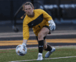 Goalkeeper in yellow jersey prepares to throw soccer ball during match on grassy field.