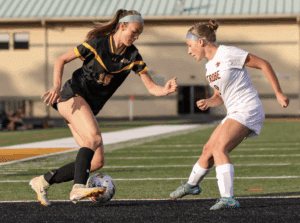 Two female soccer players in action on the field, competing for ball control during a match.