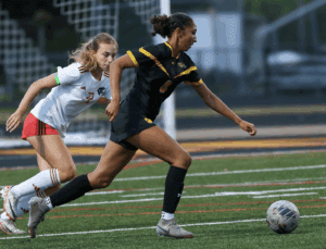 Two female soccer players competing intensely during a match on the field.