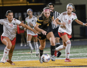 Two soccer teams competing intensely during a night match, players vying for the ball on the field.