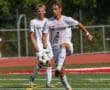 Soccer player in white uniform skillfully controls the ball on a vibrant field during a sunny match day.