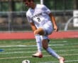 Soccer player in white North Allegheny jersey controlling ball during a game on green field.