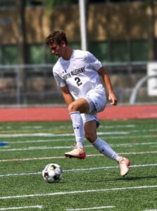 Soccer player in white North Allegheny jersey controlling ball during a game on green field.