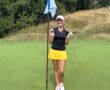 Golfer celebrating a successful hole-in-one on a sunny golf course, holding ball near flagstick.
