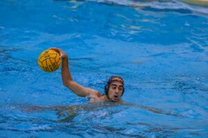 Water polo player ready to throw the ball in pool during a match.