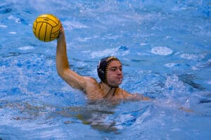 Water polo player preparing to throw ball, action shot in pool.