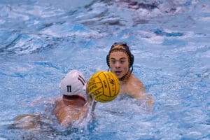 Water polo match action with two players competing for possession in a swimming pool.