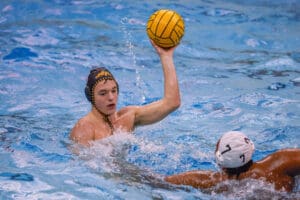 Water polo players in action, one preparing to throw the ball.