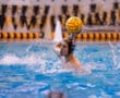 Water polo player preparing to throw the ball during a game in a swimming pool.