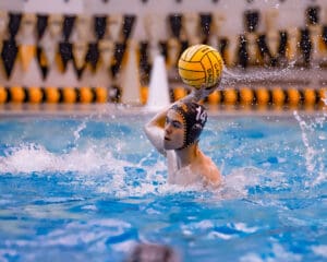Water polo player preparing to throw the ball during a game in a swimming pool.