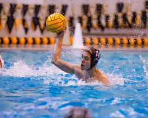 Water polo player in action, preparing to throw the ball during a competitive pool match.