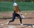 Youth softball player in yellow jersey hitting a yellow ball with a bat on a sunny field.