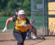 Softball player in yellow jersey runs during a game, capturing action and focus on the field.