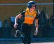 Softball player in black and yellow uniform runs during a game.