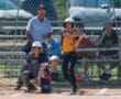 Softball player swings at pitch during game, with catcher and umpire focused in background.