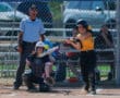 Softball batter in action, hitting a pitch during a game, with catcher and umpire observing the play.