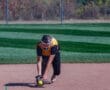 Softball player in yellow jersey fielding a ground ball on a sunny field.