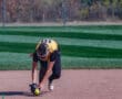 Softball player fielding a ground ball on a sunny day, focused on the game.