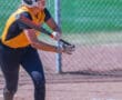 Softball player in helmet and gloves focusing on hitting the ball during a game.