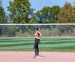 Softball player in helmet stands on second base during a game on a sunny day.