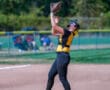 Softball player catching a ball during a game on a sunny field.