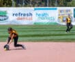 Softball player fielding ground ball on infield during game.