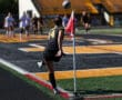 Soccer player in black jersey takes a corner kick during a match, with the ball in mid-air near the corner flag.