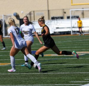 Female soccer players competing on field during a match, wearing contrasting team uniforms.