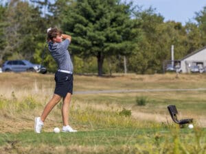 Golfer in mid-swing on a sunny course, showcasing focus and athleticism in a natural setting.