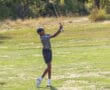 Young golfer swinging club on sunny green golf course.