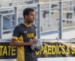 Soccer player prepares to throw in the ball during a game, wearing a black and yellow Tigers jersey.