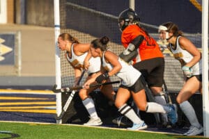 Field hockey players prepare for a corner play on the field, focused and ready for action.