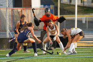 Field hockey players in action near the goal during a competitive match.