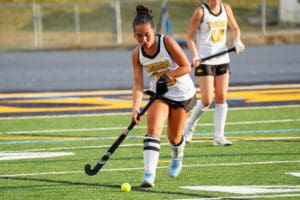 Field hockey player controlling the ball during a competitive match on a sunny day.