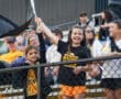 Children enjoying a sports event, waving a flag with excitement in the stadium stands.