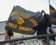 Fans waving North Allegheny field hockey flags at a game, promoting school spirit.