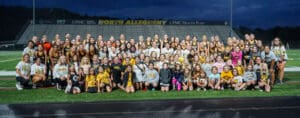 Large group of students and athletes in sports uniforms on a field at North Allegheny stadium.