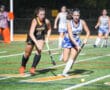Girls field hockey match between Tigers and Spartans, focusing on players competing for the ball.