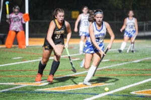 Girls field hockey match between Tigers and Spartans, focusing on players competing for the ball.